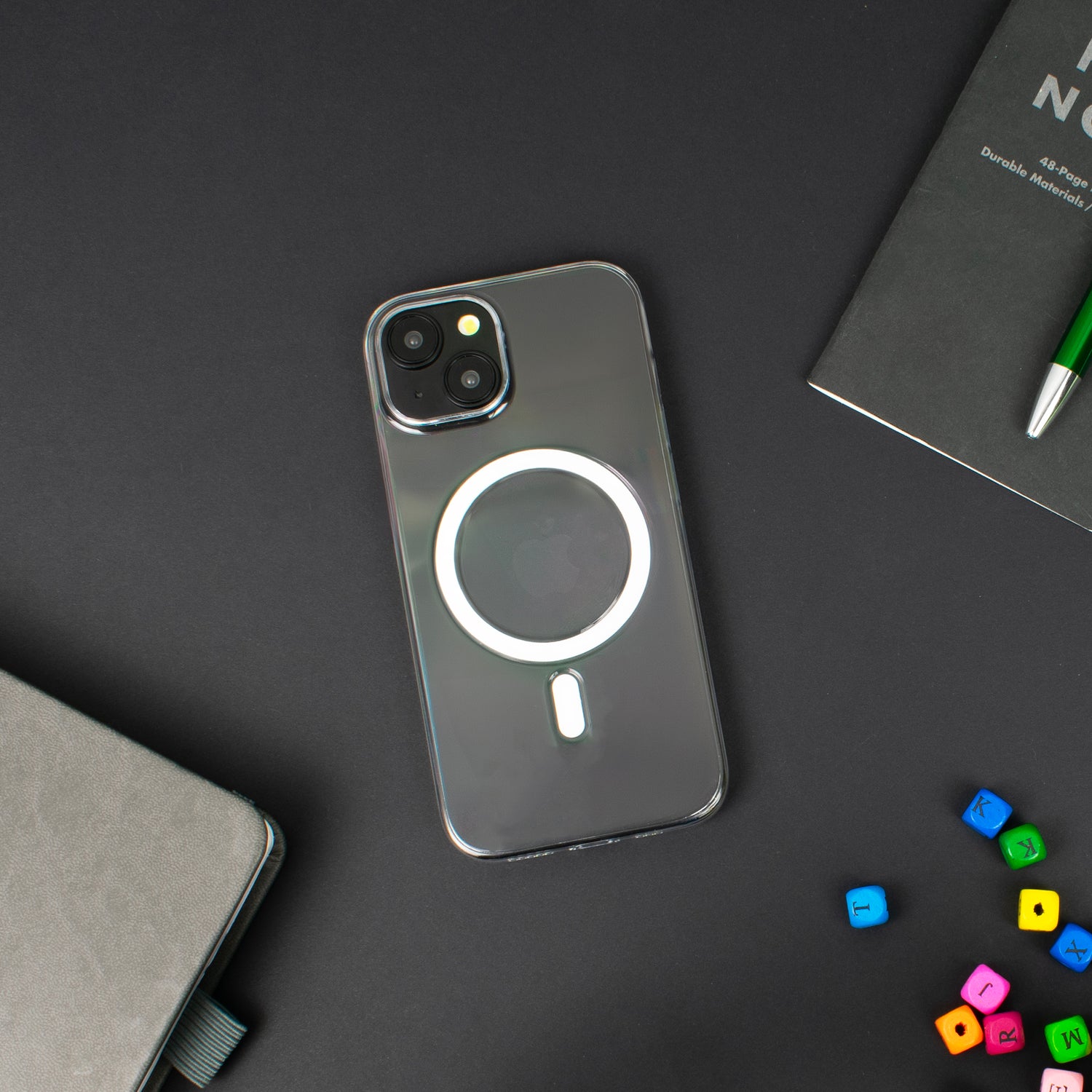 A lifestyle image of the SKNS CLEAR Magnetic iPhone 15 case on a desk showing off the slim and clear design