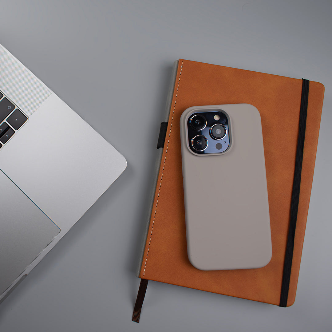 Lifestyle image of The Slate SKNS Silicone Case fitted to the iPhone 14 Pro on a office desk journal