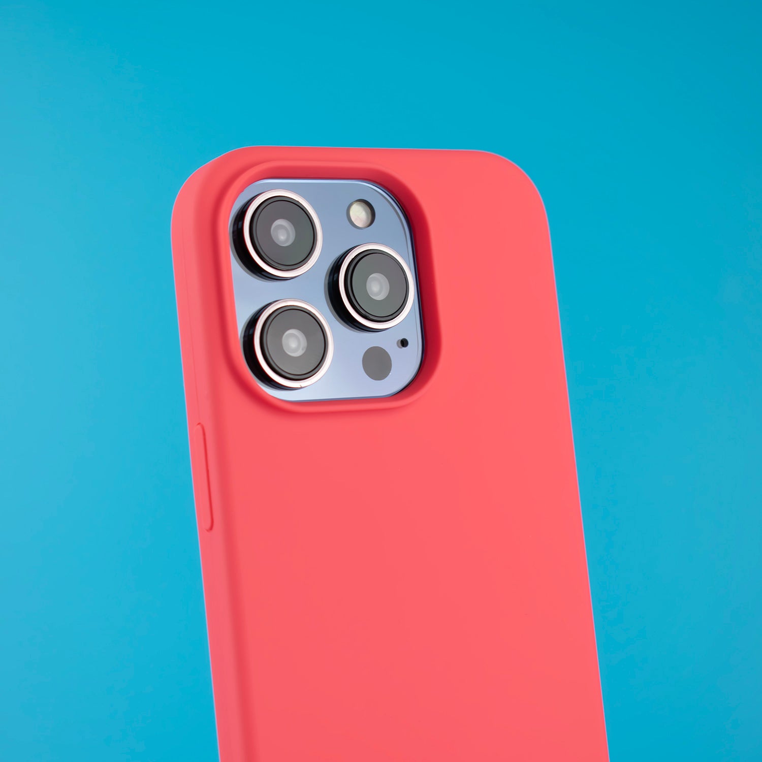 Angled vibrant lifestyle shot of the SKNS SILICONE case on the iPhone 14 Pro Max showcasing the raised lip around the camera