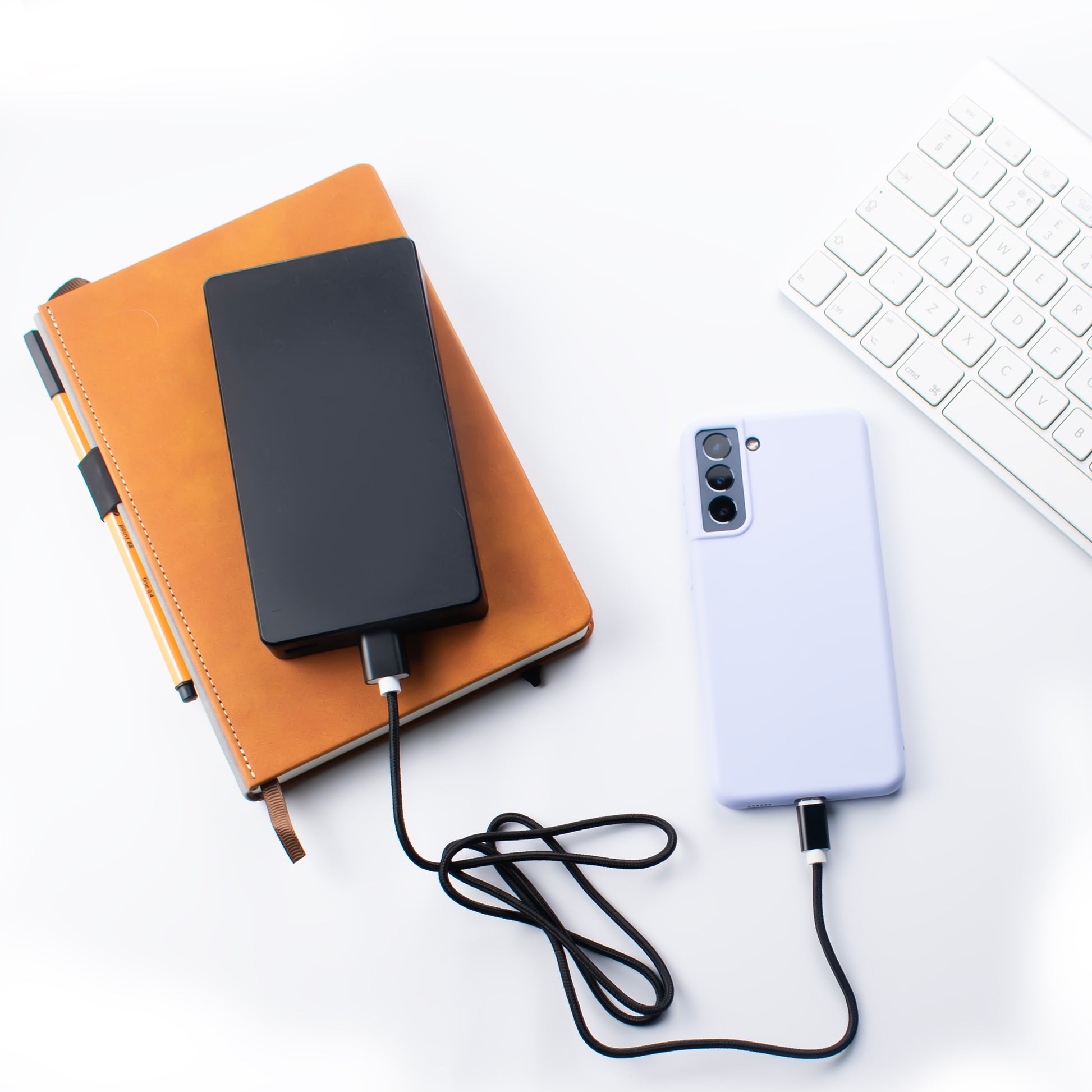 lifestyle image of the SKNS Nylon micro usb cable connected to a samsung S22 being charged through a power bank on a office desk